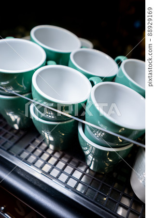 set of ceramic colored cups or mugs heating on professional coffee machine set of ceramic colored cups or mugs heating on professional coffee machine 88929169