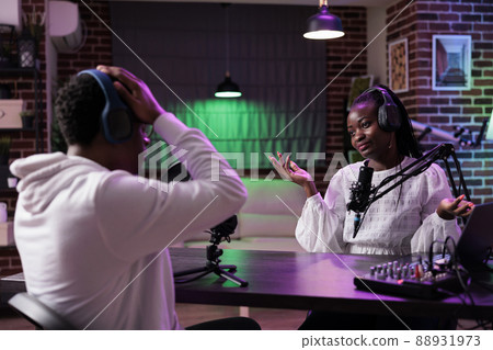 Podcast host interviewing male influencer on show episode, recording discussion for content. Woman having fun with person, doing livestream and chatting, broadcasting with sound equipment. Podcast host interviewing male influencer on show episode, recording discussion for content. Woman having fun with person, doing livestream and chatting, broadcasting with sound equipment. 88931973