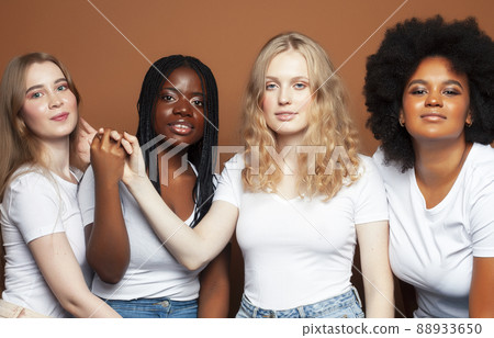 young pretty african and caucasian women posing cheerful together on brown background, lifestyle diverse nationality people concept 88933650