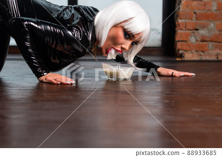 A sexy woman in a short white wig and a latex suit drinks milk from the floor as a cat. Role-playing games 88933685