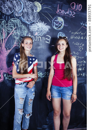 back to school after summer vacations, two teen girls in classroom with blackboard painted 88933791