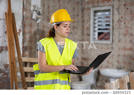 Woman with laptop on indoor construction site Woman with laptop on indoor construction site 88934325