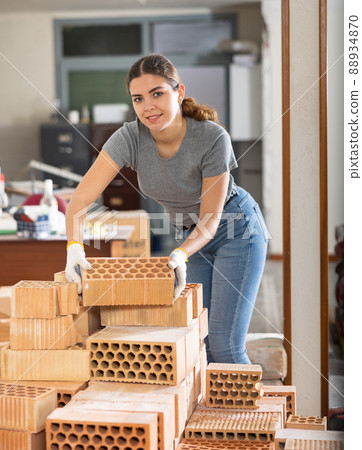 Girl stacking red bricks in her apartment during renovations Girl stacking red bricks in her apartment during renovations 88934870