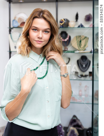 Woman trying on necklace from green jadeite Woman trying on necklace from green jadeite 88934874