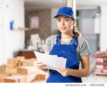 Female contractor checking blueprints and taking notes at building site Female contractor checking blueprints and taking notes at building site 88934966
