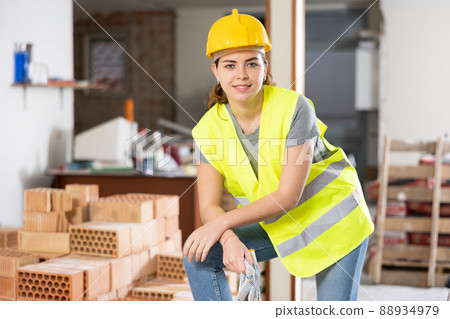 Confident female builder in yellow vest and hard hat at construction site Confident female builder in yellow vest and hard hat at construction site 88934979