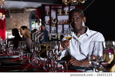 African-american man with glass of white wine is expecting woman in a luxury restaurant 88935155