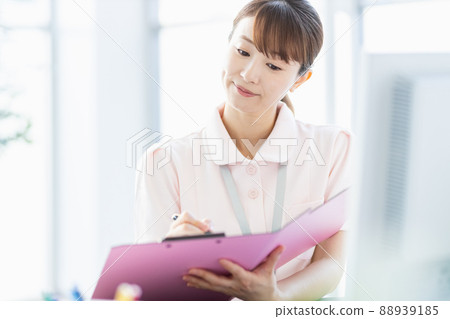 Healthcare worker woman filling out a file in the facility Healthcare worker woman filling out a file in the facility 88939185