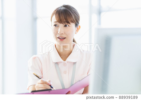 Healthcare worker woman filling out a file in the facility 88939189