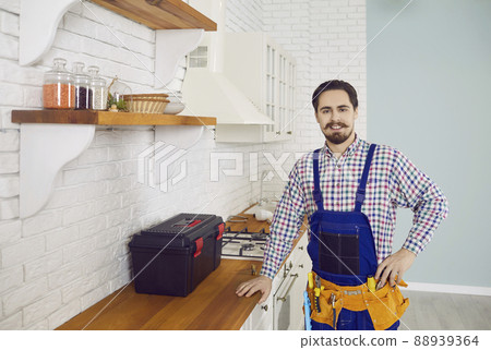Portrait of a happy young plumber or repairman during maintenance work in the kitchen 88939364