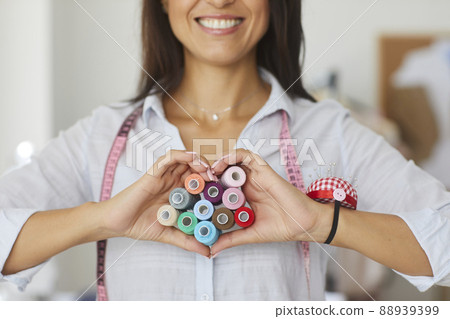Smiling seamstress show heart love hand gesture Smiling seamstress show heart love hand gesture 88939399