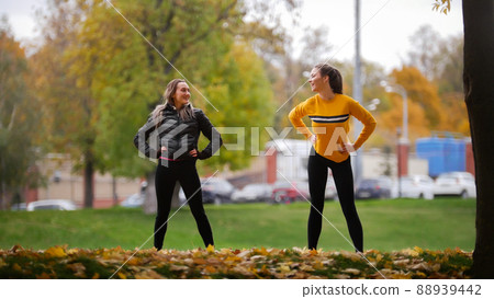 Girls warming up outside before training in park. Hands to the sides. Autumn. Girls warming up outside before training in park. Hands to the sides. Autumn. 88939442