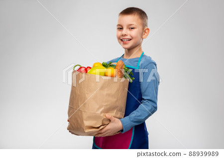 smiling boy in apron holding paper bag with food smiling boy in apron holding paper bag with food 88939989