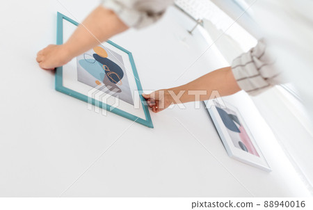 close up of hands hanging picture in frame on wall 88940016