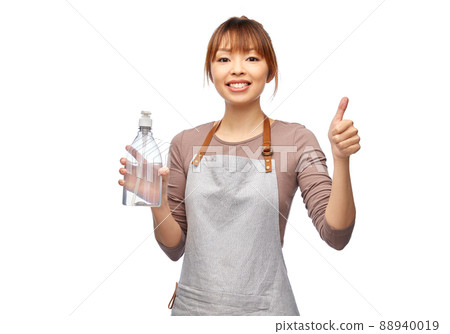 happy woman in apron with hand sanitizer or soap 88940019