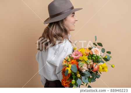 happy woman in felt hat holding bunch of flowers 88940223