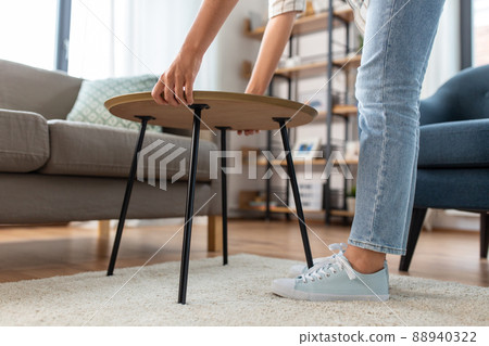woman placing coffee table next to sofa at home 88940322