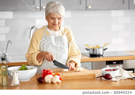 happy woman chopping champignons on kitchen 88940324