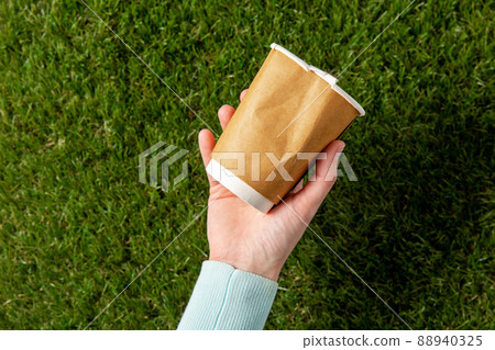 close up of hand picking coffee cup from grass close up of hand picking coffee cup from grass 88940325