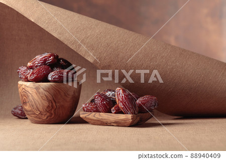 Juicy dates in wooden dishes on a brown background. Juicy dates in wooden dishes on a brown background. 88940409