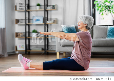 smiling senior woman exercising on mat at home 88940415