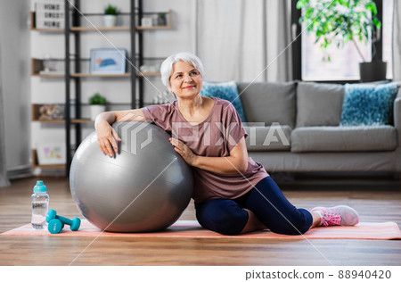 smiling senior woman with exercise ball at home smiling senior woman with exercise ball at home 88940420