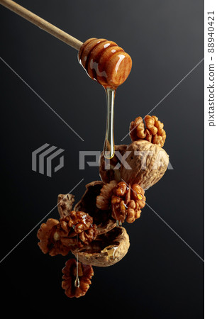 Honey drops onto walnuts. 88940421
