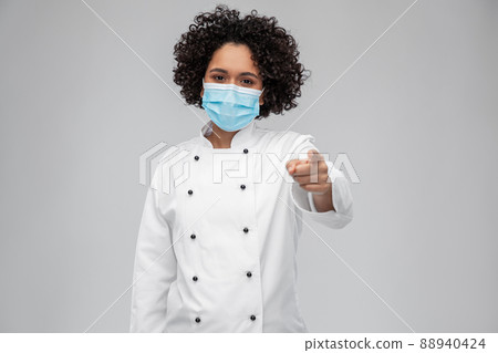 female chef in medical mask pointing to camera 88940424