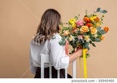 woman with flowers sitting on chair from back woman with flowers sitting on chair from back 88940460