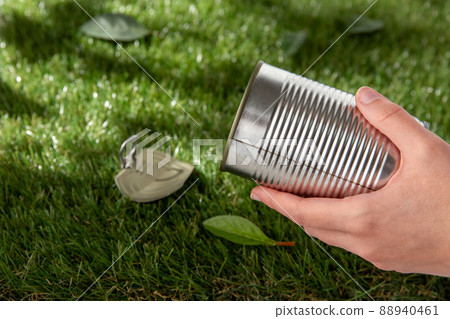 close up of hand removing used tin can from grass close up of hand removing used tin can from grass 88940461