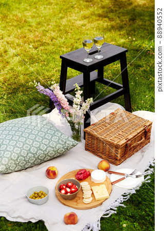 food, drinks and picnic basket on blanket on grass food, drinks and picnic basket on blanket on grass 88940552