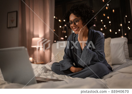 happy woman with laptop sitting in bed at night happy woman with laptop sitting in bed at night 88940670