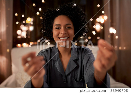 happy woman with sparklers sitting in bed at night 88940708