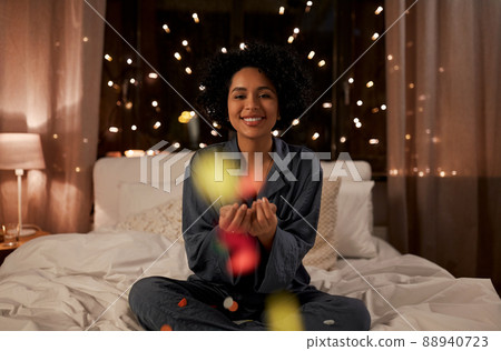 woman blowing confetti in bed at night at home woman blowing confetti in bed at night at home 88940723