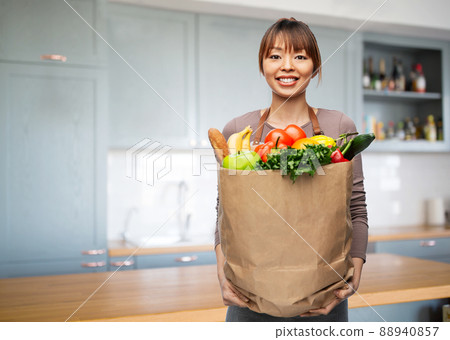 happy woman with food in paper bag on kitchen 88940857