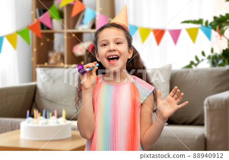 smiling girl in birthday party hat with blower 88940912