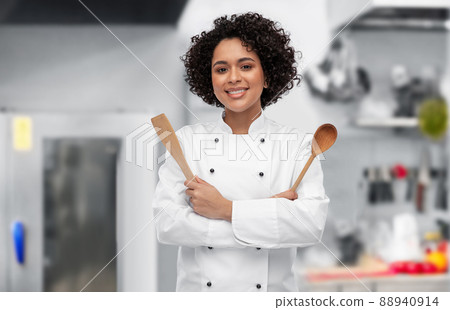 smiling female chef with wooden spoon and spatula 88940914