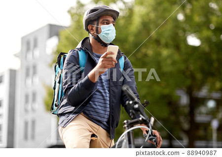 delivery man in mask with smatphone riding bicycle delivery man in mask with smatphone riding bicycle 88940987
