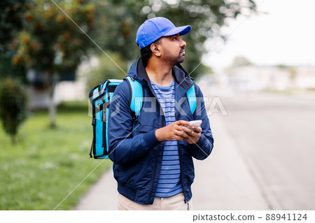 indian delivery man with bag and phone 88941124