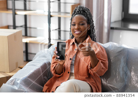 woman with phone moving home and showing thumbs up woman with phone moving home and showing thumbs up 88941354