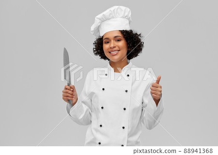 female chef in toque with knife showing thumbs up female chef in toque with knife showing thumbs up 88941368
