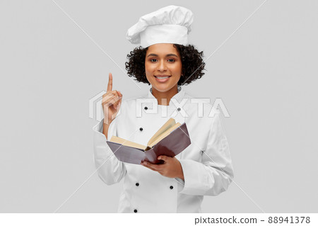 happy female chef in white toque reading cook book happy female chef in white toque reading cook book 88941378