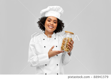 smiling female chef holding jar with pasta smiling female chef holding jar with pasta 88941379
