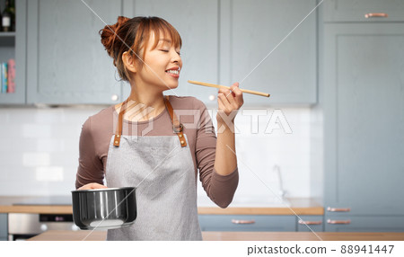 happy woman in apron with saucepan in kitchen 88941447