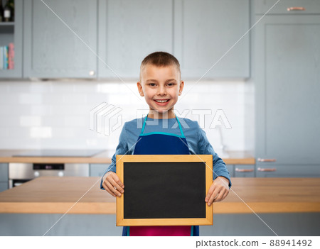 smiling little boy in apron holding chalkboard smiling little boy in apron holding chalkboard 88941492