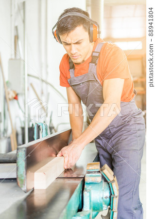Concentrated woodworker trimming wooden plank in workshop Concentrated woodworker trimming wooden plank in workshop 88941804