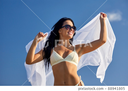 woman in bikini swimsuit with cover-up over sky woman in bikini swimsuit with cover-up over sky 88941805