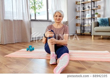 smiling senior woman exercising on mat at home smiling senior woman exercising on mat at home 88942105