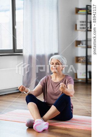 happy senior woman meditating on mat at home happy senior woman meditating on mat at home 88942117