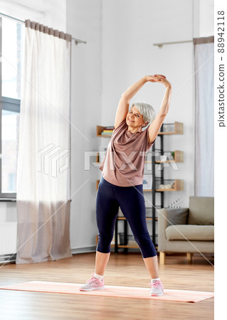 smiling senior woman exercising on mat at home 88942118